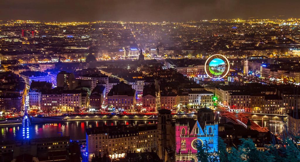 Lyon illuminated at night with buildings and river reflections