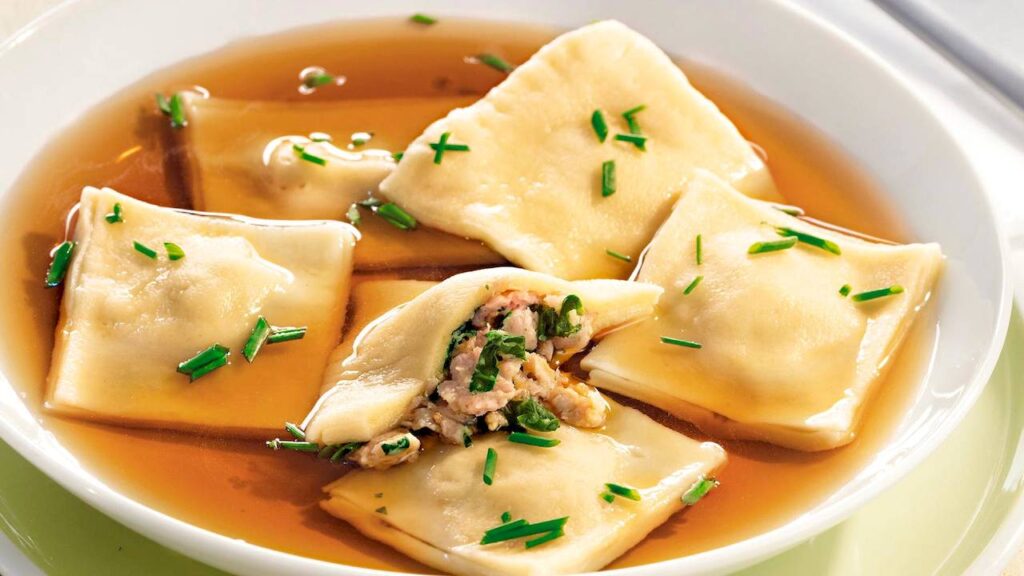 Traditional Swabian Maultaschen served in broth with fresh herbs