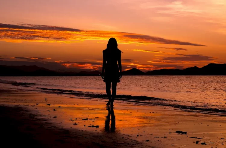silhouette of a person standing on a beach at sunset