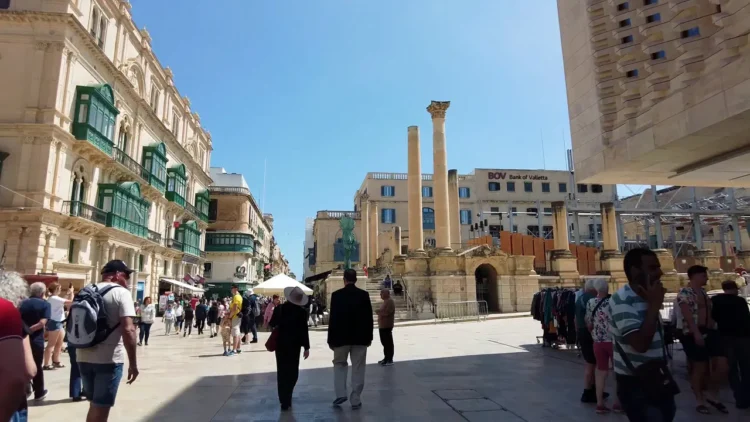 Charming narrow street in Valletta with traditional colorful balconies and limestone buildings