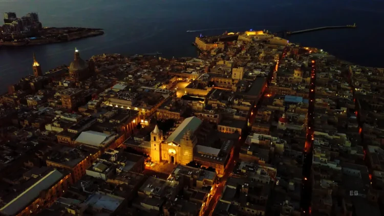 Valletta's illuminated bastions and Grand Harbour at night, reflecting on calm waters