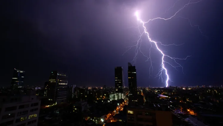 Dangerous lightning storm over city with dark clouds