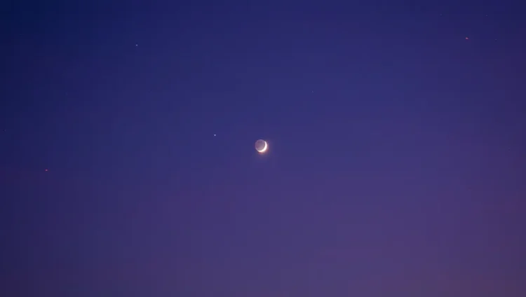 Crescent Moon glowing faintly over Earth symbolizing silent night sky